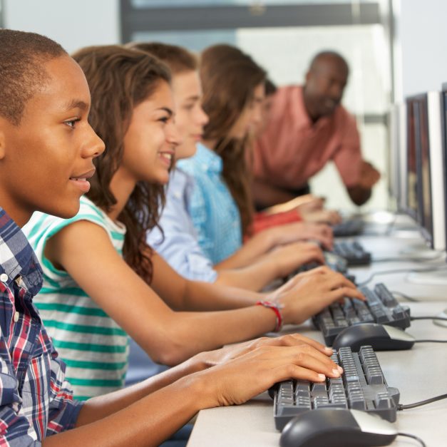 Group Of Students Working At Computers In Classroom