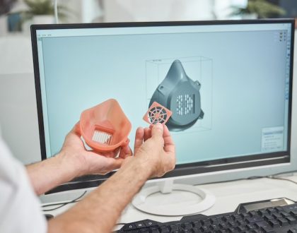 Man holding 3d printed object alongside computer with 3d print design file