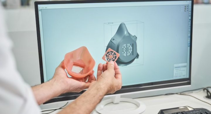 Man holding 3d printed object alongside computer with 3d print design file