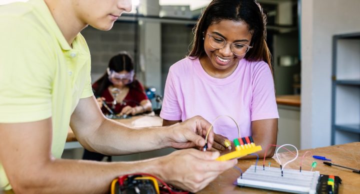 Teacher and student measuring the voltage of an electrical experiment.